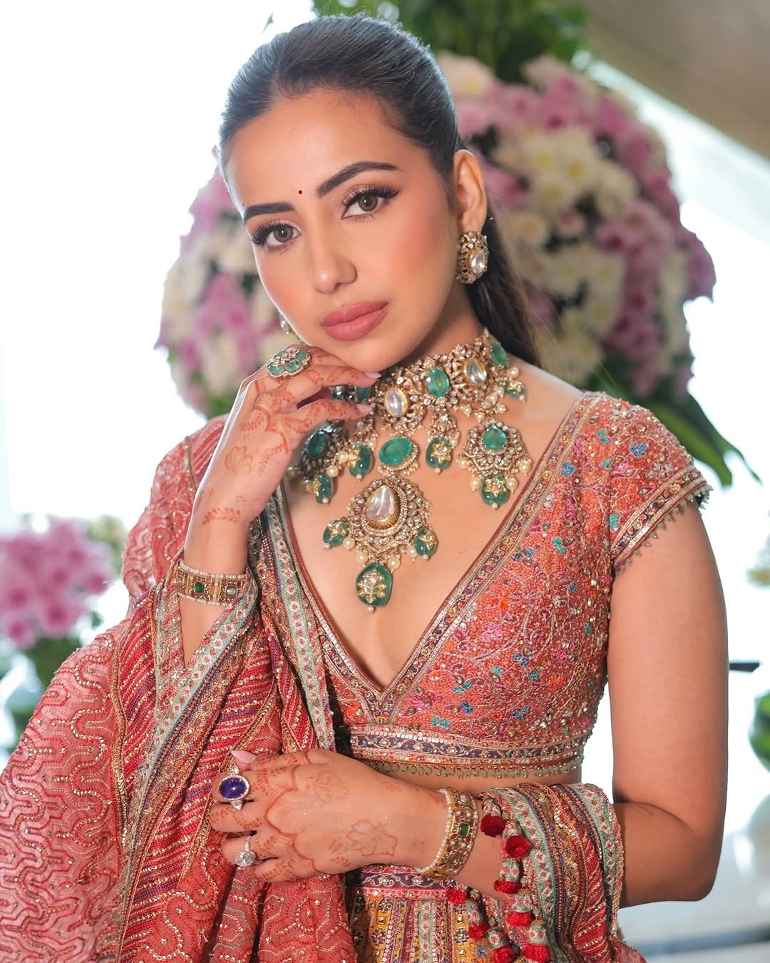 Indian bridal makeup in Dubai with defined eyes, soft pink lips, statement emerald jewellery and an embellished bridal outfit