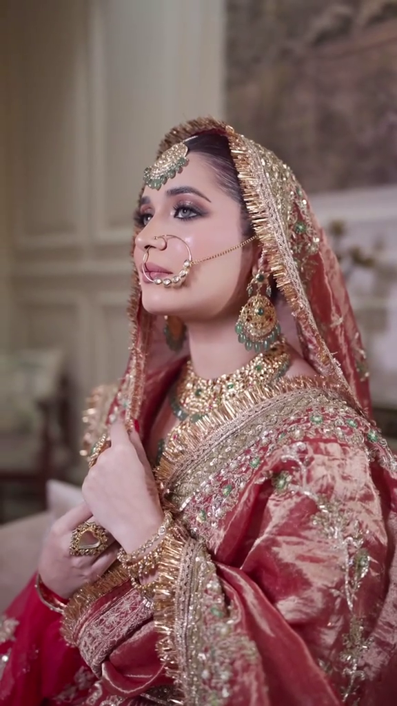 Pakistani bridal makeup in Dubai with smokey eyes, traditional red bridal styling, nath and gold jewellery