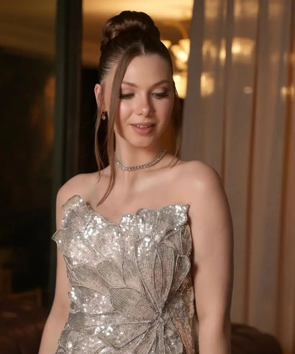 Soft evening glam with luminous skin, neutral eyes, nude lips and an elegant high bun